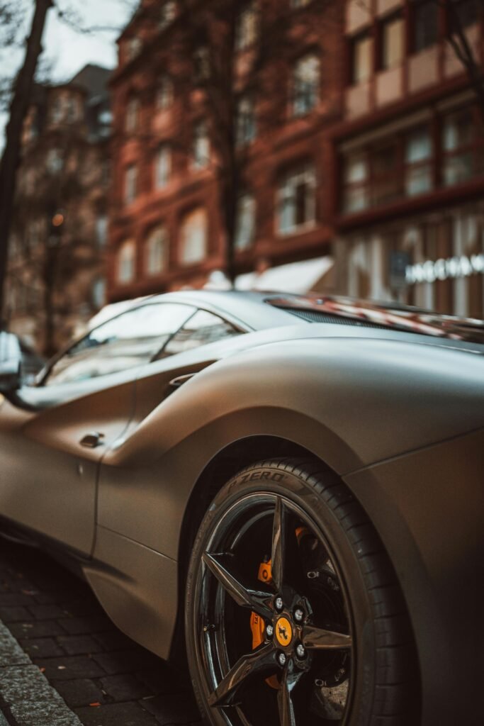 A stylish gray supercar parked in a vibrant city street, showcasing urban luxury and automotive elegance.